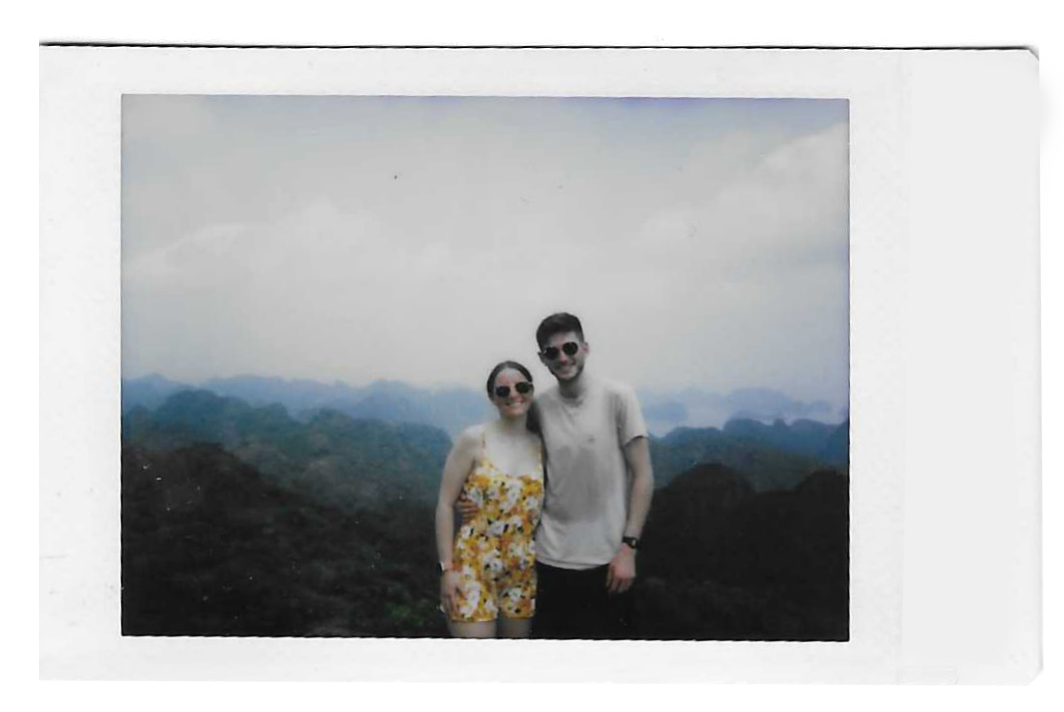 Polaroid photo of a couple posing together on a bed with the date 06/10/19 written on the polaroid.